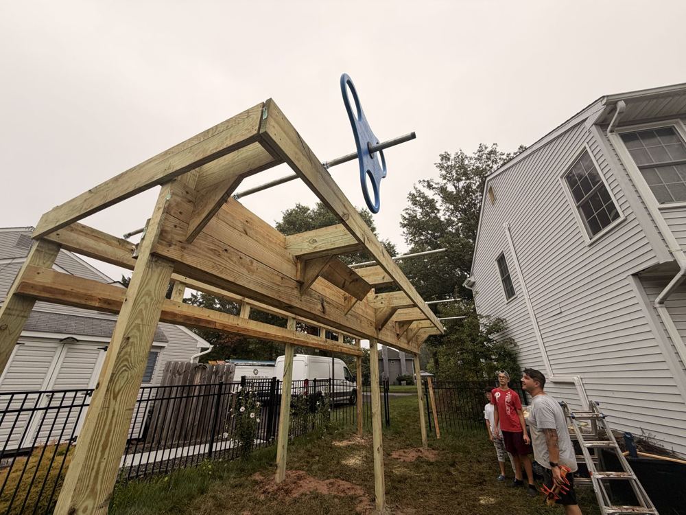 Natural wood ninja rig frame with angled corner braces beside a house